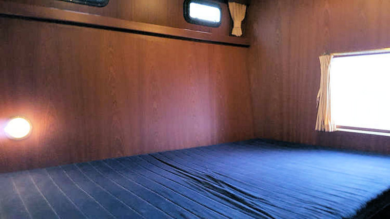 Tweepersoons bed in een achterkajuit van de boot Julia